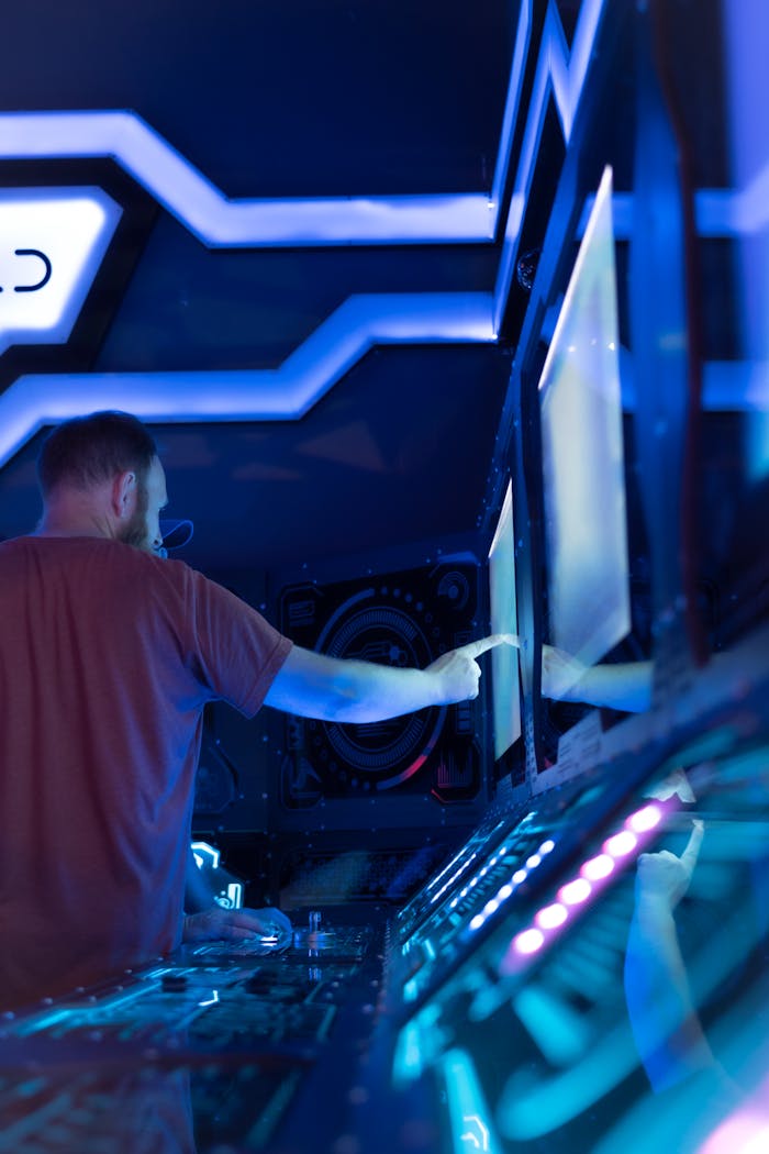 A man interacts with glowing monitors in a neon-lit futuristic studio setting.